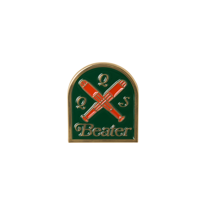 Pin with crossed red beater sticks on a green background