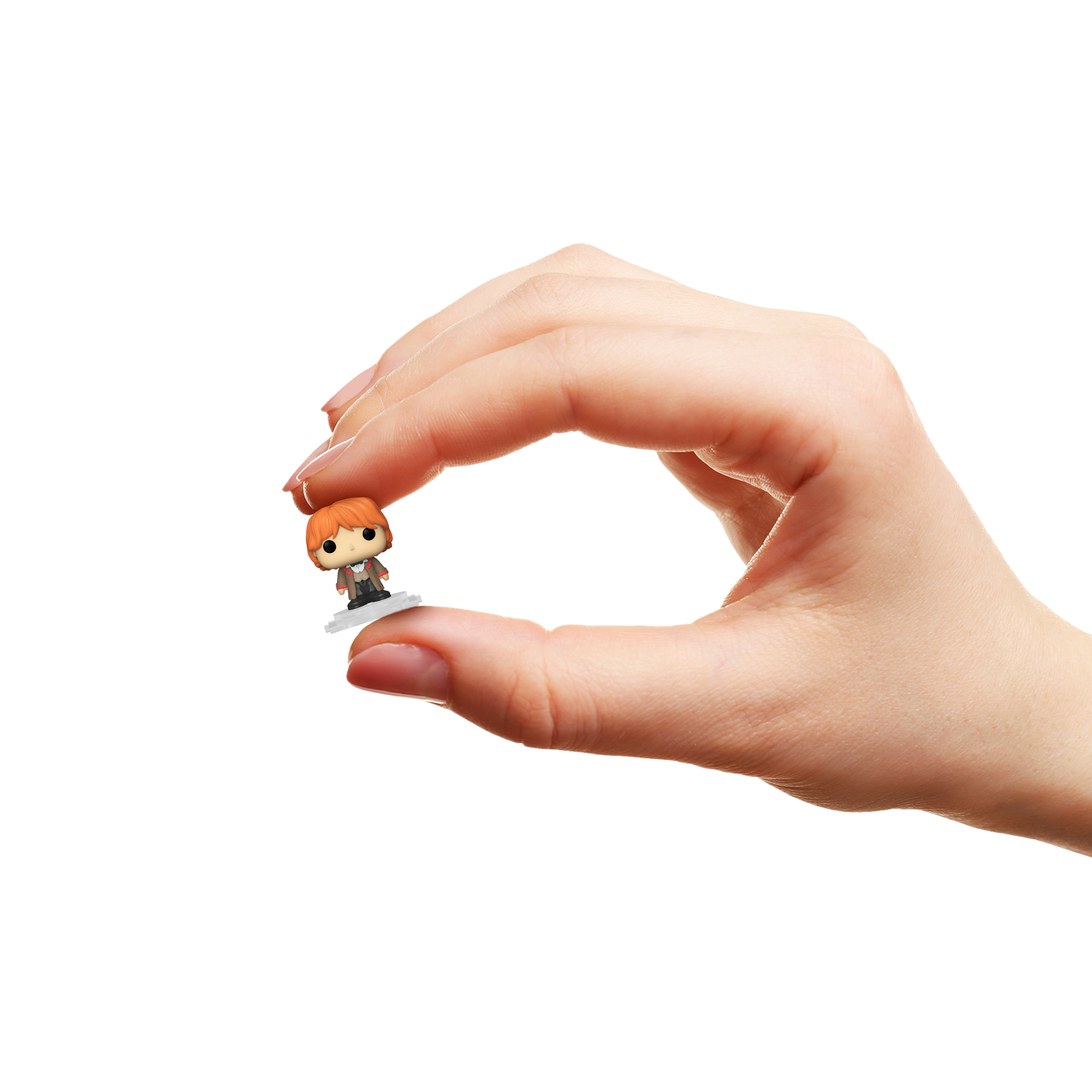 Hand holding a small figurine of Ron Weasley against a white background