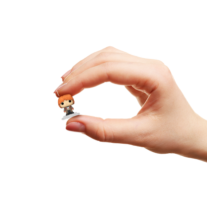 Hand holding a small figurine of Ron Weasley against a white background