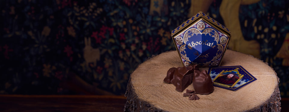 Chocolate Frog and Honeydukes box on a wooden surface with a tapestry background