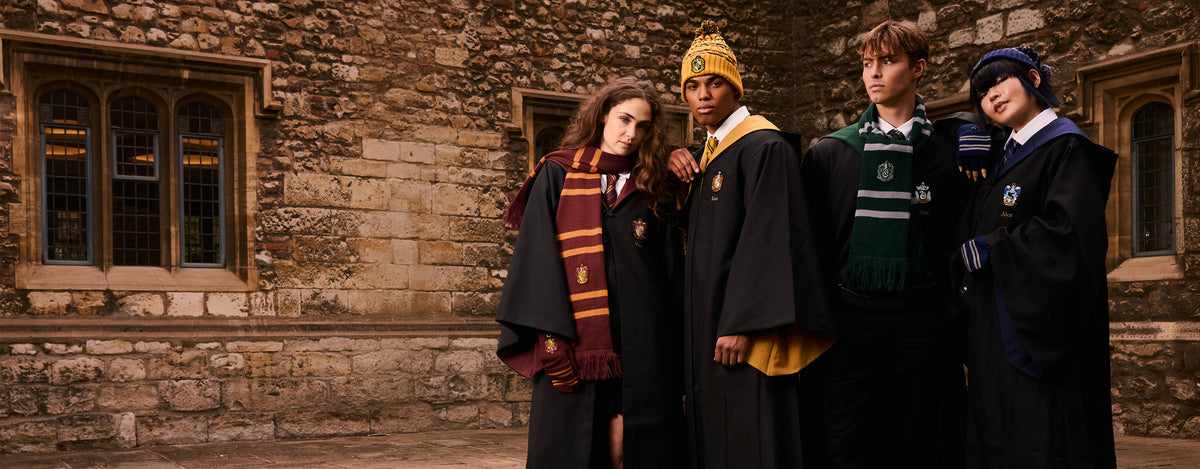 Four individuals in Harry Potter-themed costumes standing in front of a stone building.