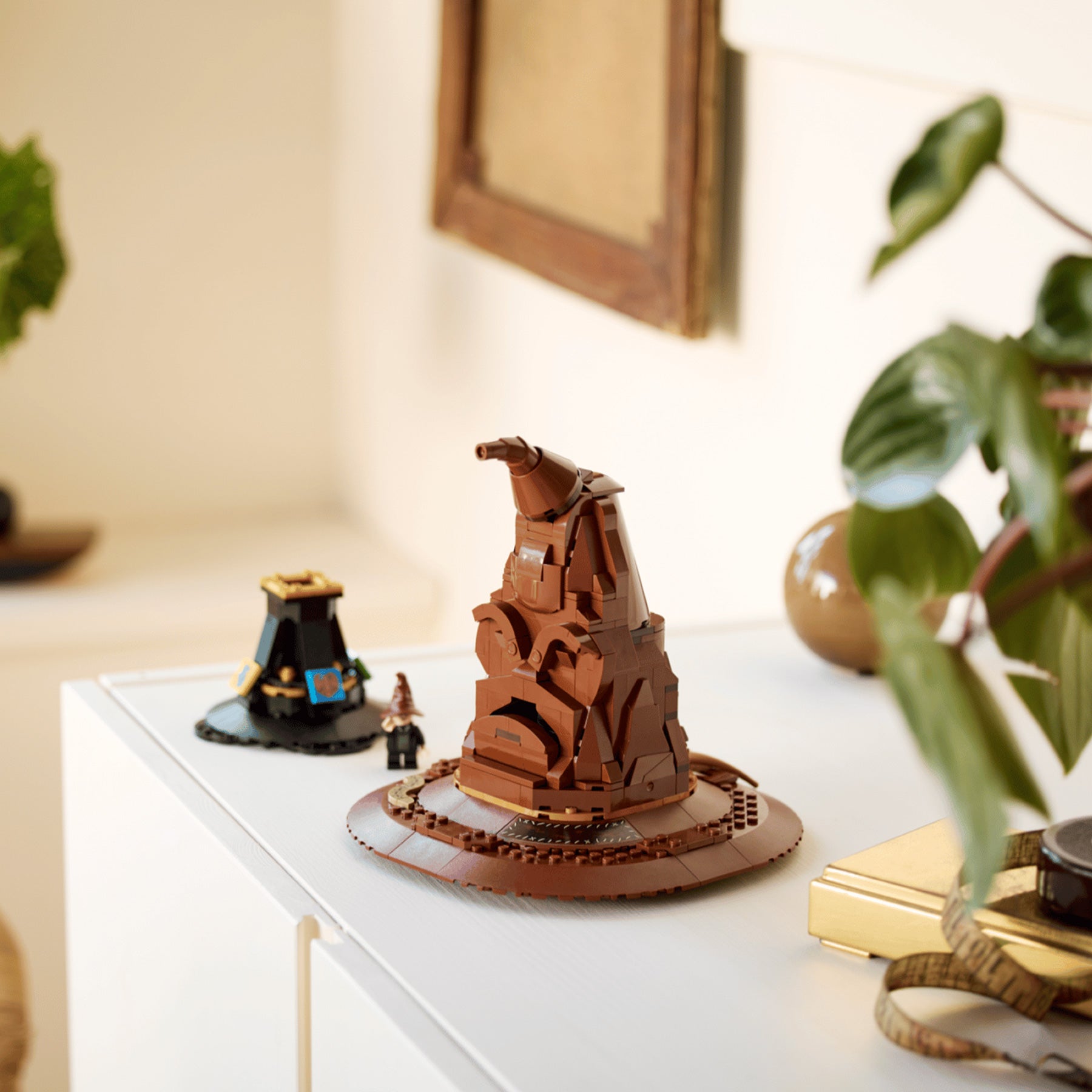 Brown Talking Sorting Hat LEGO on a white surface with decorative items and plants.